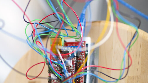 Circuit board with wires sticking out of it sitting on a table