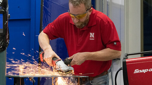 Instructor using grinder tool as sparks fly