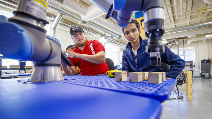 Jacob Hansen, with ALA engineering and a Nebraska alumni, and Kunjan Theo Joseph with the UNL MAARS Lab, work at making their robotic arm program stack blocks. The programming would simulate a larger robotic arm stacking pallets. Nebraska Innovation Studios is working with robotic arms and teaching students and local industry people how to use them.